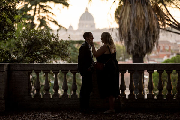 Low-key image of newly-engaged couple at the Pincio Gardens at sunset with the Vatican in the background