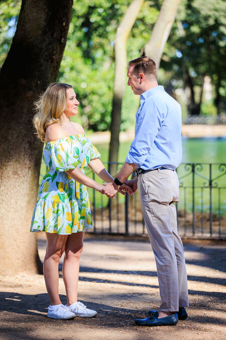 Beautiful couple  holding hands moments before his surprise proposal at lake in Villa Borghese in Rome