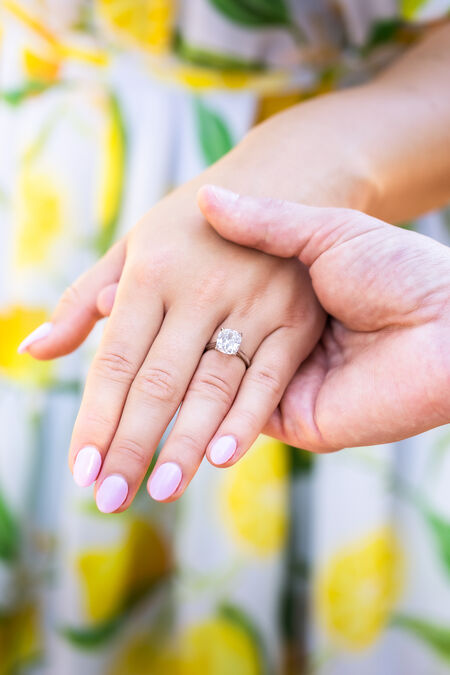 Close-up of fiance holding his fiancée's hands with a beautiful engagement ring