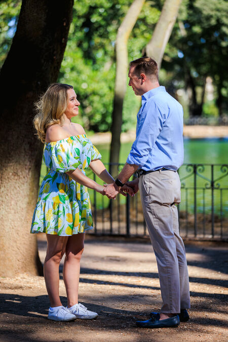 Beautiful couple  holding hands moments before his surprise proposal at lake in Villa Borghese in Rome