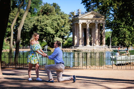 Beautiful couple during their surprise marriage proposal at the lake in Villa Borghese in Rome