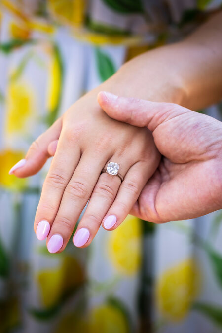 Close-up of fiance holding his fiancée's hands with a beautiful engagement ring