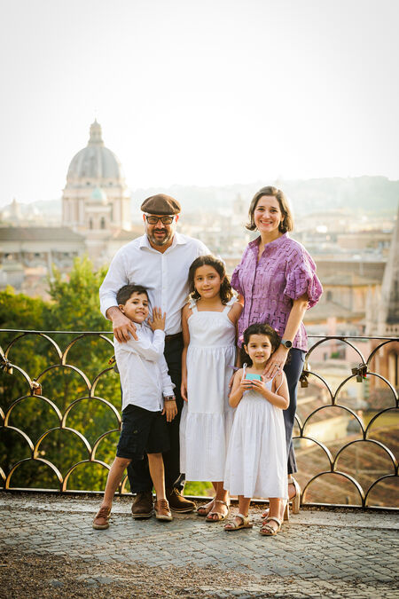 Newly-engaged couple with their 3 kids posing on the Terrazza Belvedere at sunset in Rome