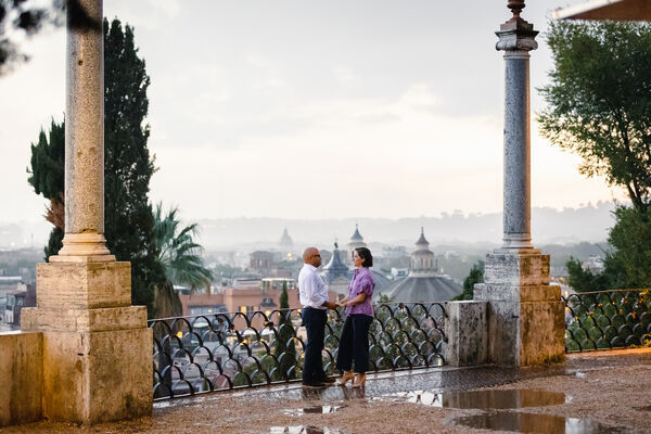 Newly-engaged couple holding hands during their surprise wedding proposal photo shoot on the Terrazza Belvedere in Rome