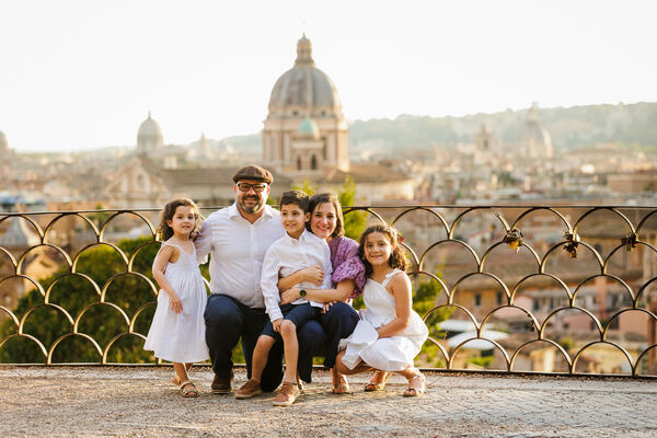 Beautiful family squatting on the Terrazza Belvedere in Rome during their surprise wedding proposal at sunset