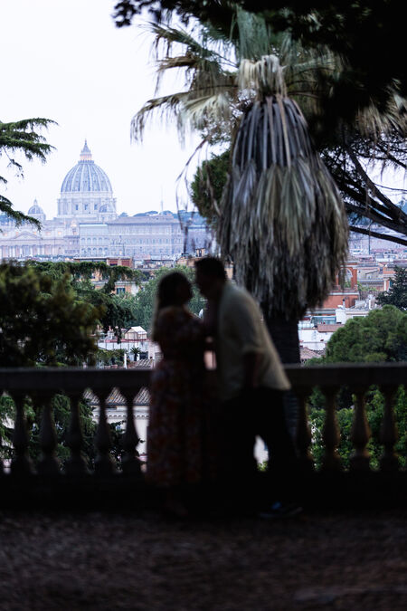 Newly-engaged couple kissing each other at the Pincio Gardens with the Vatican in the background