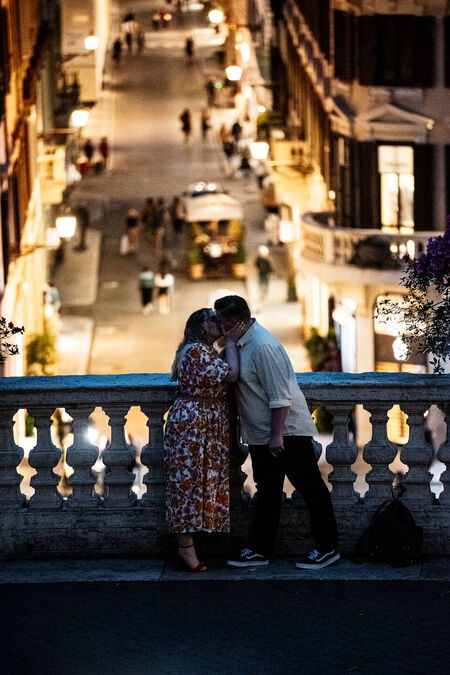Newly-engaged couple kissing each other on the Spanish Steps at dusk