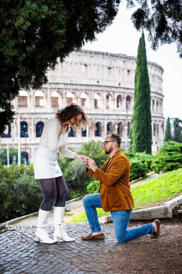 Man kneeling down during his wedding proposal in Rome with a view on the Colosseum