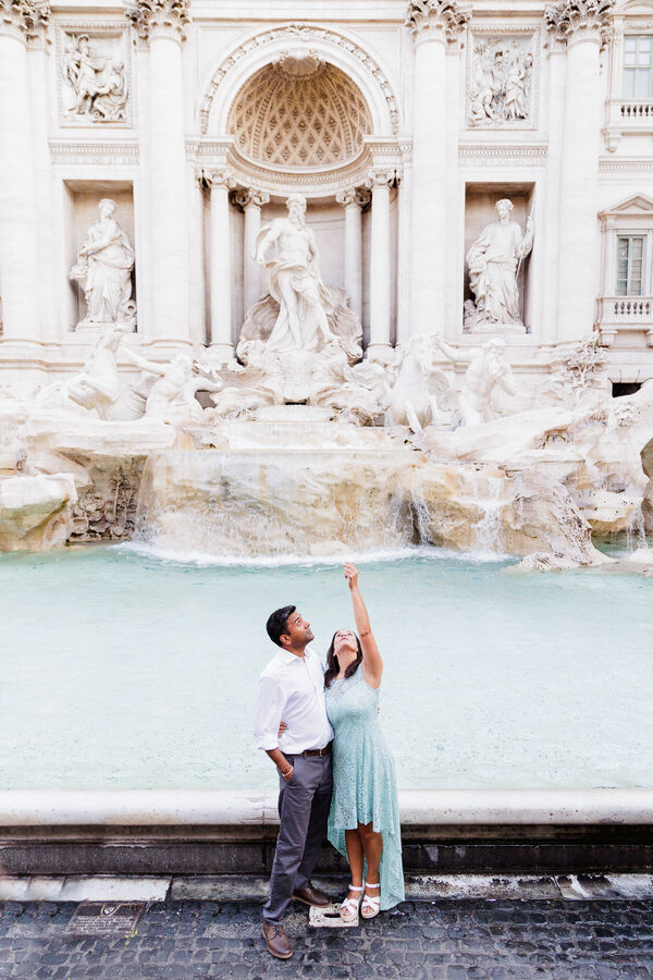 Newly-engaged couple tossing the coin into the Trevi Fountain in Rome 