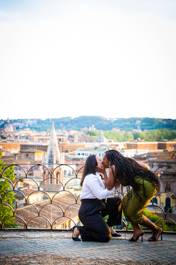 Lesbian couple kissing during their surprise wedding proposal photoshoot at the Pincio Gardens in Rome