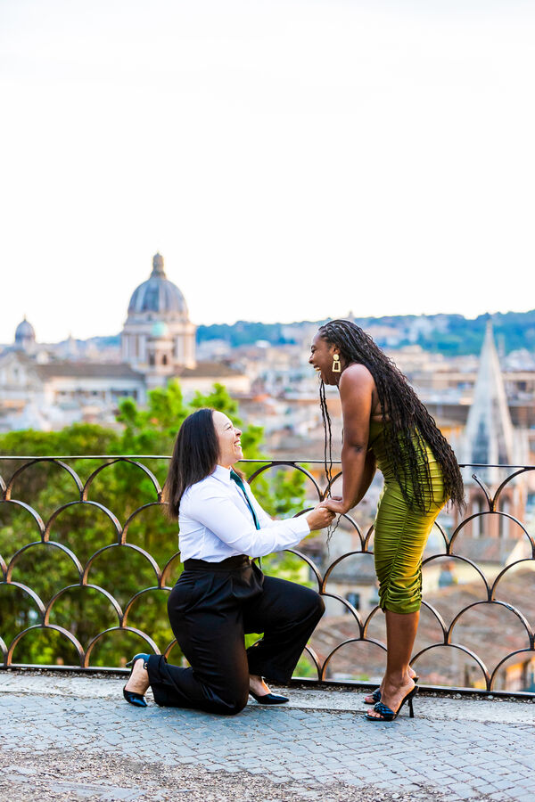 Female gay couple during their surprise marriage proposal in Rome on the Terrazza Belvedere at sunset