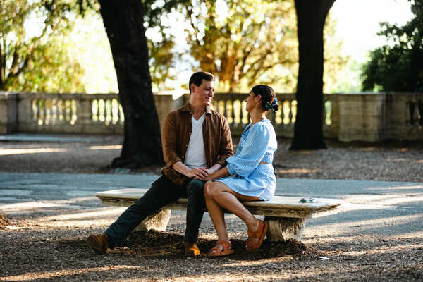 Newly-engaegd couple sitting on a bench in the Pincio Gardens during their surprise proposal photoshoot in Rome