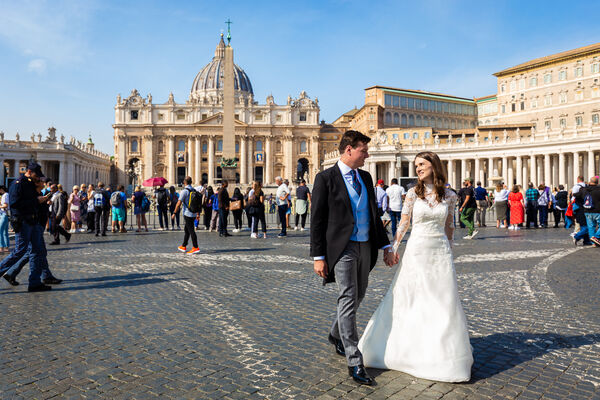 Sposi Novelli walking holding hands with the Vatican in the background