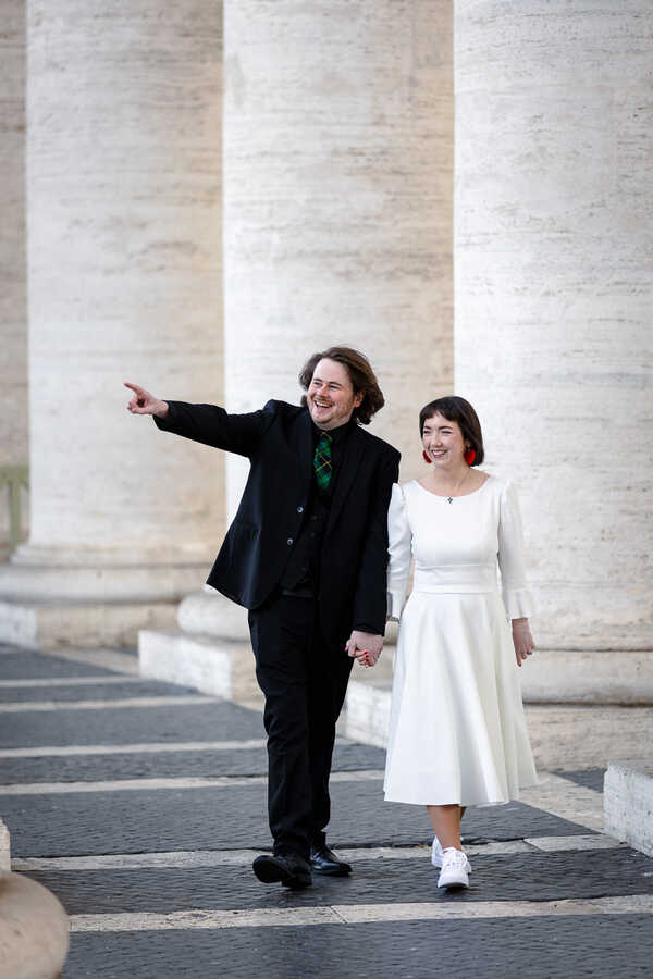 Happy Sposi Novelli couple walking hand in hand under the Colonnade in Saint Peter's Square in Rome