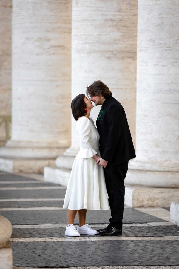 Sposi Novelli couple kissing under the Colonnade in Saint Peter's square in Rome