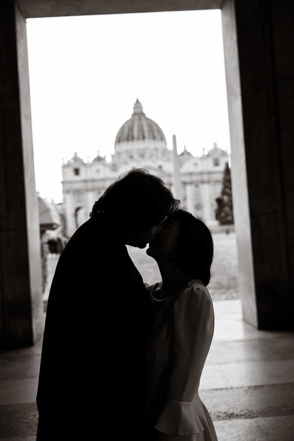 Black and white picture of newly-wed couple kissing with the Vatican in the background during their Sposi Novelli Photoshoot in Rome