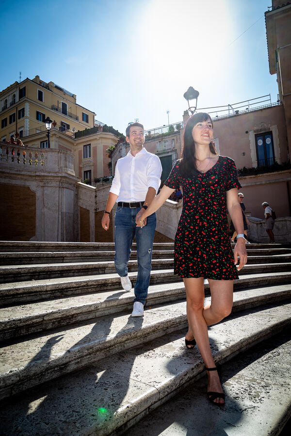 Couple holding their hands climbing down the Spanish Steps while on their vacation photoshoot in Rome
